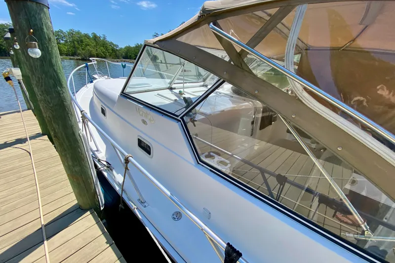 Slide: The Image of 2002 Mainship Pilot 34 docked, showcasing sleek design and spacious deck under clear skies. - 8