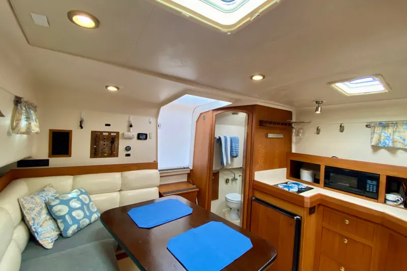 Slide: The Image of Interior of 2002 Mainship Pilot 34 yacht featuring cozy seating, kitchenette, and bathroom. - 20
