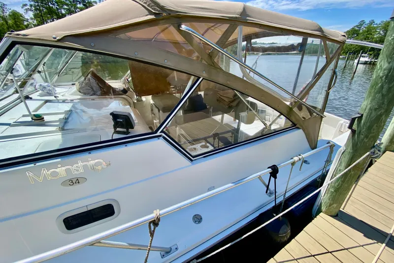 Slide: The Image of 2002 Mainship Pilot 34 docked, featuring tan canopy and sleek design. - 5