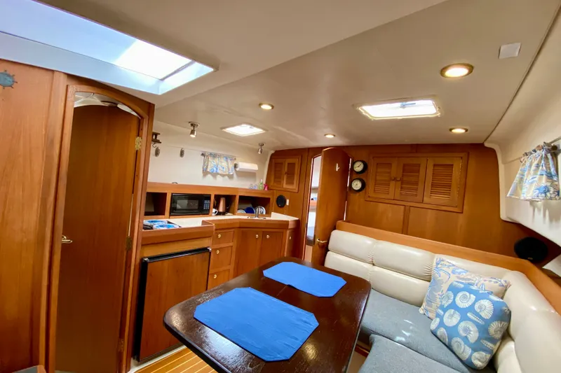 Slide: The Image of 2002 Mainship Pilot 34 interior with cozy seating, kitchenette, and wooden cabinetry. - 21
