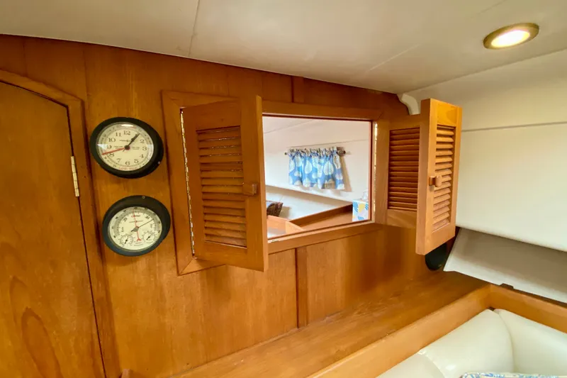 Slide: The Image of 2002 Mainship Pilot 34 cabin interior with wooden paneling, clock, and nautical decor. - 34