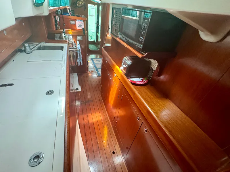Slide: The Image of Interior of 1996 Beneteau Oceanis 40 CC yacht with wooden cabinetry and modern appliances. - 16