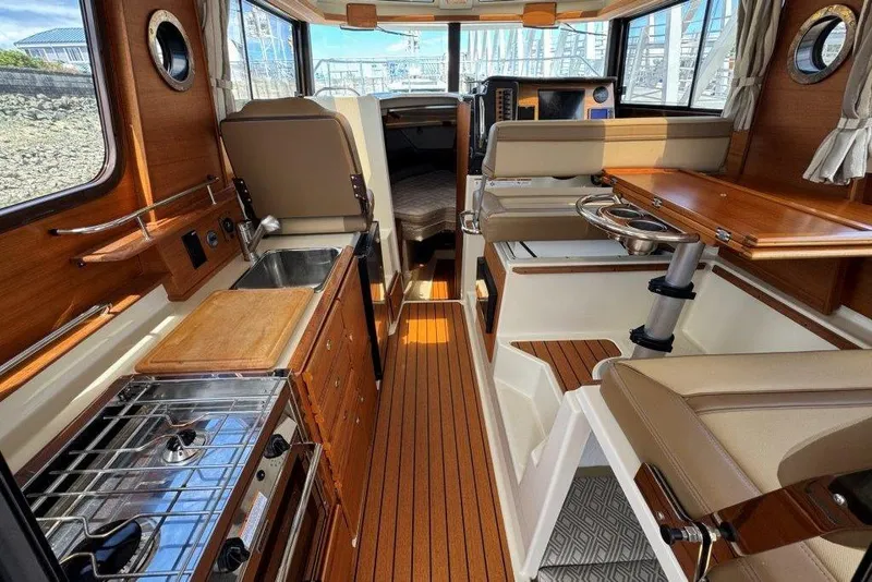 Slide: The Image of Interior of 2022 Ranger Tugs R-27 boat with wood accents and compact kitchen area. - 5