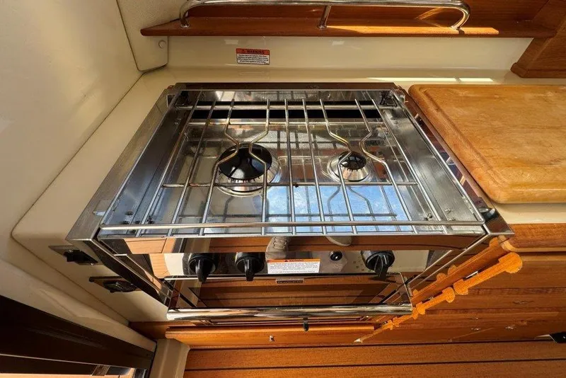 Slide: The Image of 2022 Ranger Tugs R-27 boat kitchen with stainless steel stove and wooden countertop. - 8