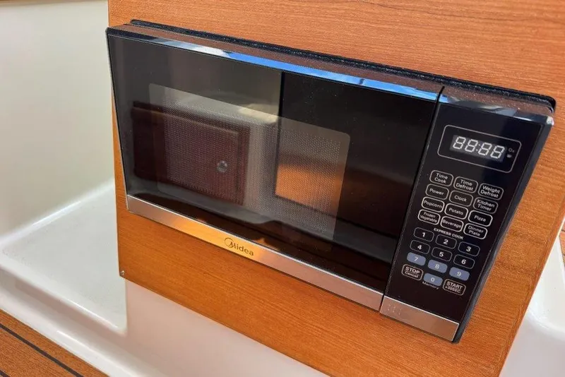 Slide: The Image of Microwave oven inside 2022 Ranger Tugs R-27 boat, featuring digital controls and wood paneling. - 11