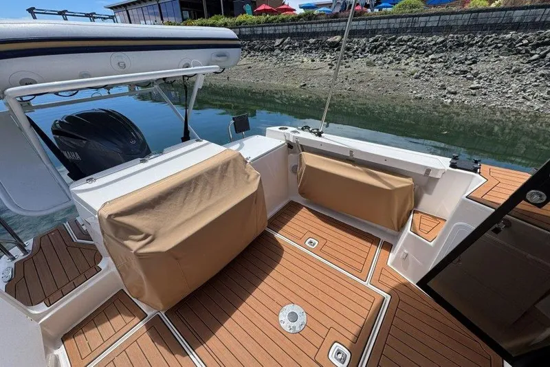 Slide: The Image of 2022 Ranger Tugs R-27 boat deck with covered seating and outboard motor. - 4