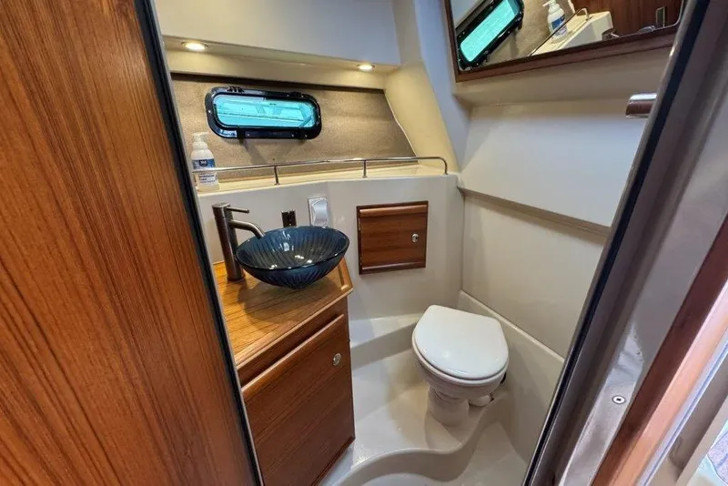 Slide: The Image of 2022 Ranger Tugs R-27 bathroom with modern sink, toilet, and wooden cabinetry. - 26