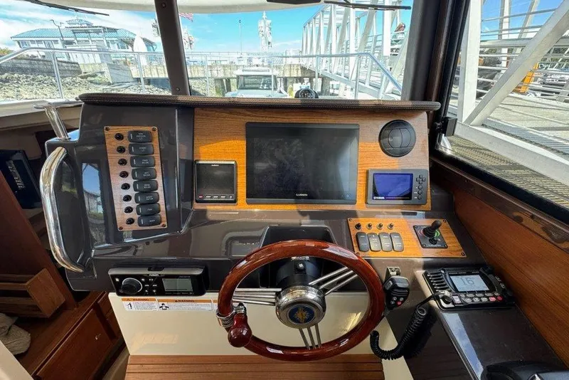 Slide: The Image of 2022 Ranger Tugs R-27 helm with modern navigation equipment and wooden steering wheel. - 16