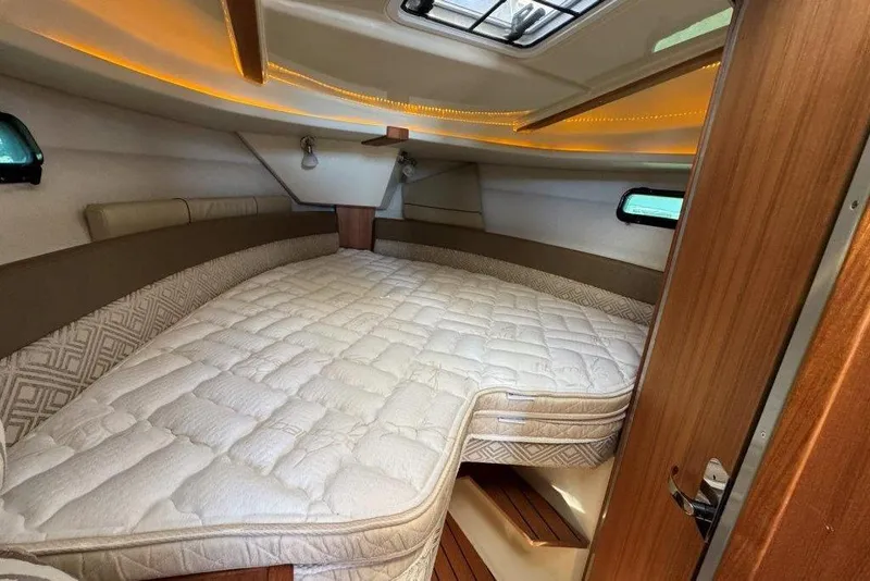 Slide: The Image of 2022 Ranger Tugs R-27 cabin interior with cozy bed and ambient lighting. - 24