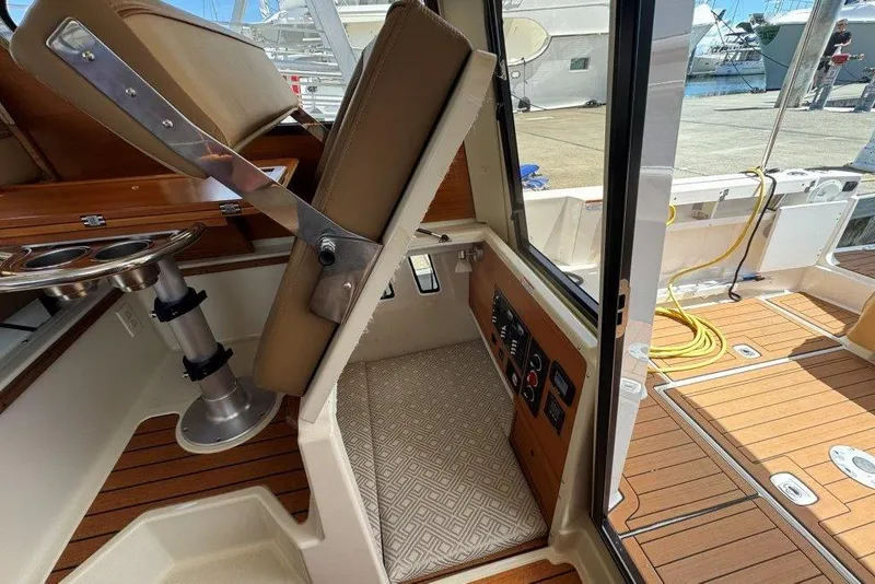 Slide: The Image of 2022 Ranger Tugs R-27 interior with helm seat, control panel, and teak flooring. - 29
