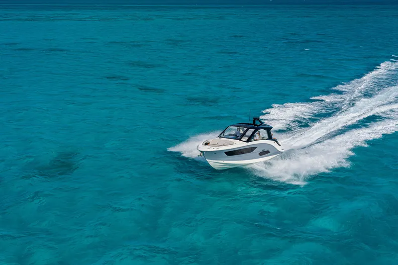 Slide: The Image of A 2026 Sea Ray Sundancer 370 Outboard speeds across clear, turquoise water. - 11