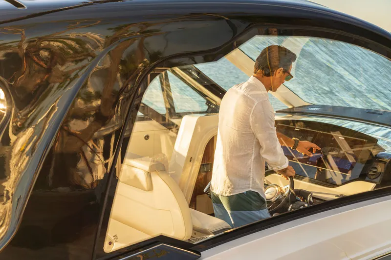 Slide: The Image of A man stands at the helm of a Sea Ray Sundancer 370 Outboard, overlooking the sea. - 22