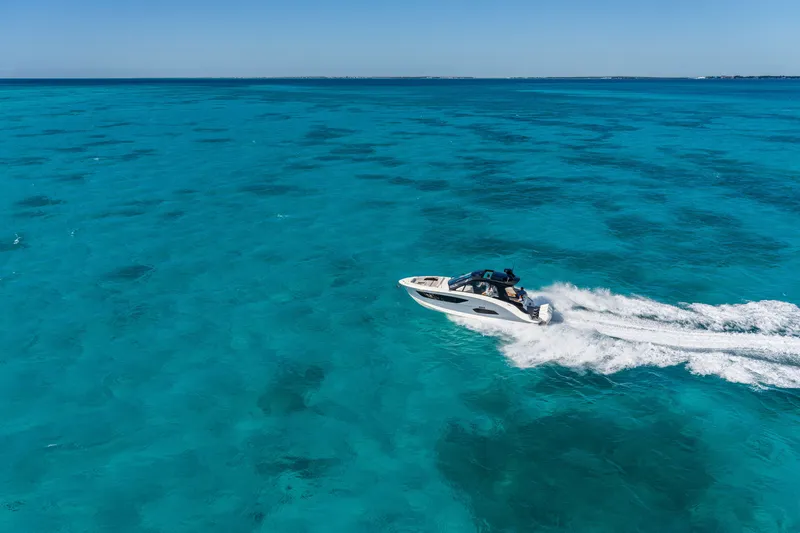 Slide: The Image of A 2026 Sea Ray Sundancer 370 Outboard speeds across turquoise waters. - 7