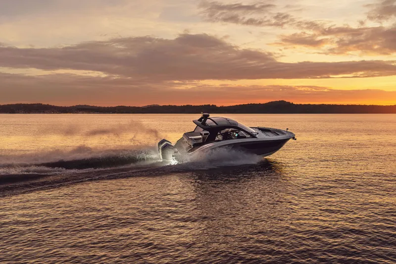 Slide: The Image of A 2026 Sea Ray Sundancer 370 Outboard cruising on calm water at sunset. - 2