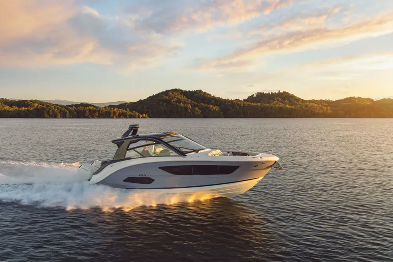 Slide: The Image of A 2026 Sea Ray Sundancer 370 Outboard speeds across calm water at sunset. - 27