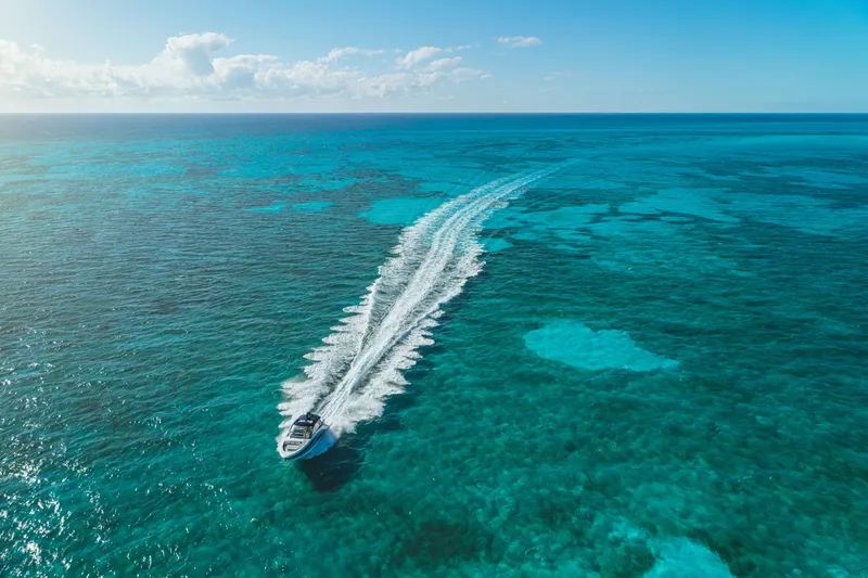 Slide: The Image of A 2026 Sea Ray Sundancer 370 Outboard speeds across turquoise water under a clear sky. - 10