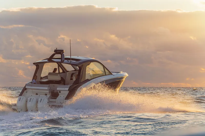 Slide: The Image of A 2026 Sea Ray Sundancer 370 Outboard cruising through the sea at sunset, surrounded by waves. - 31