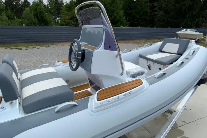 Slide: The Image of 2027 Gala V420 inflatable boat with modern seating and steering, parked outdoors. - 11