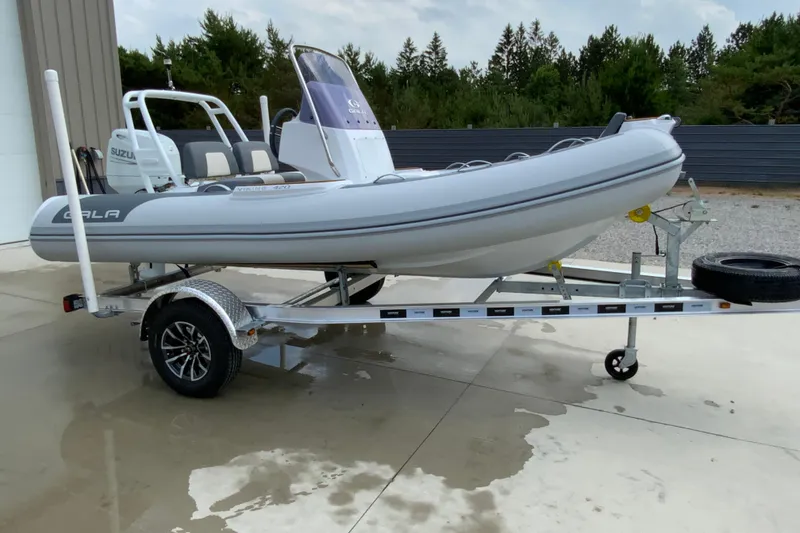 Slide: The Image of 2027 Gala V420 inflatable boat on trailer, parked outdoors near trees. - 8