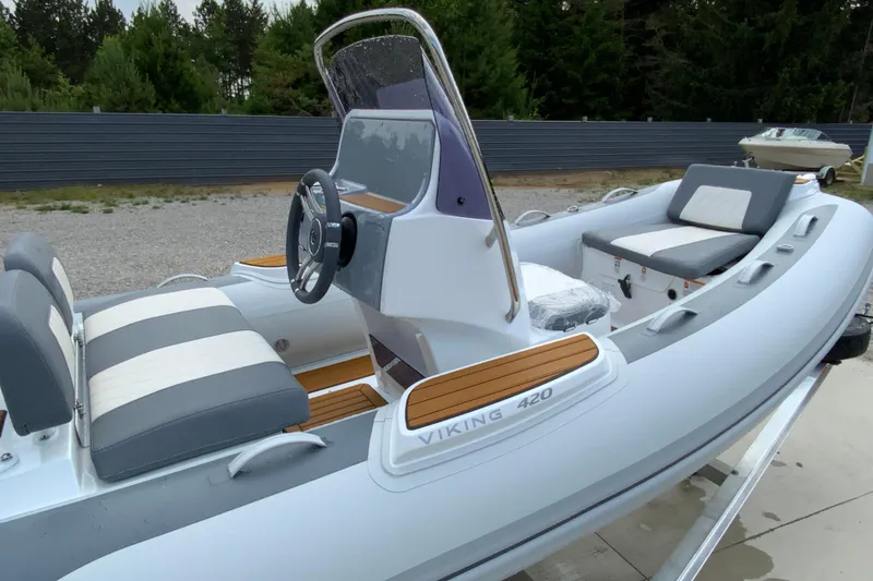 Slide: The Image of Inflatable boat Gala V420, 2027 model, with cushioned seating and steering console, parked outdoors. - 10