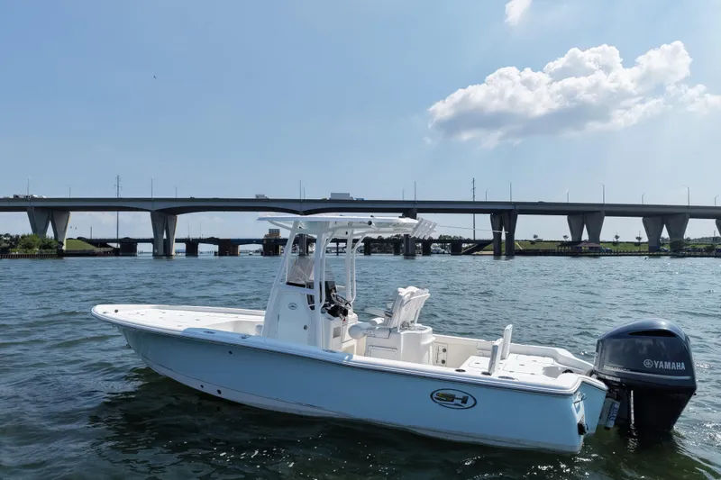 Slide: The Image of 2017 Sea Hunt BX 25 BR boat on water near a bridge under a clear sky. - 2