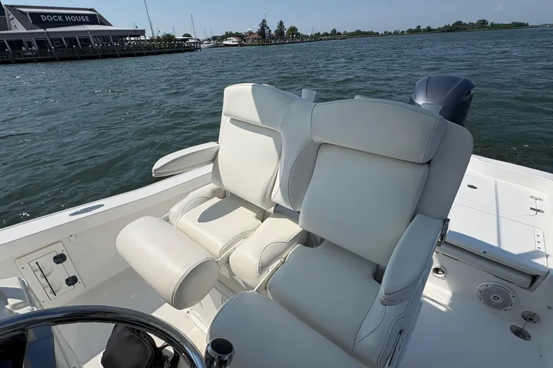 Slide: The Image of 2017 Sea Hunt BX 25 BR boat with white seating, dock house in background. - 6