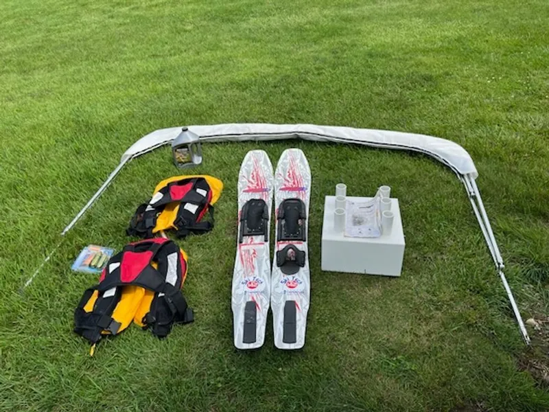 Slide: The Image of Two life jackets, a pair of water skis, a bimini top, and accessories laid out on grass. - 19