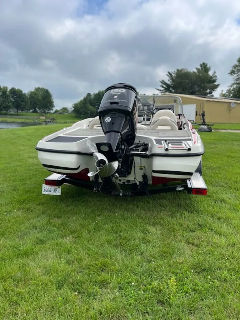 Slide: The Image of A white motorboat on a trailer sits on grass, surrounded by trees. - 24
