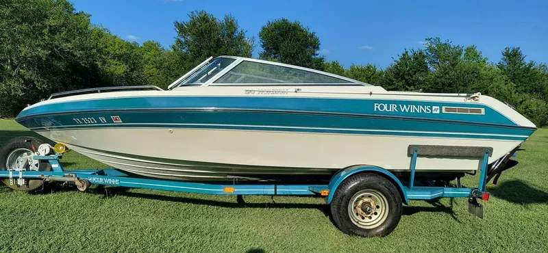 The Image of A 1992 Four Winns 190 Horizon on a trailer, surrounded by trees and grass. - 0
