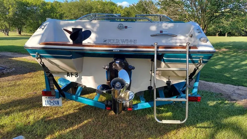 Slide: The Image of Rear view of a 1992 Four Winns 190 Horizon boat on a trailer, surrounded by grass. - 6