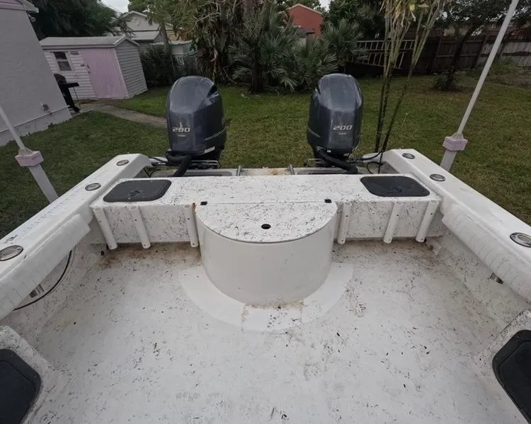 Slide: The Image of 2004 Twin Vee 26 Center Console boat with dual outboard motors in a backyard setting. - 34
