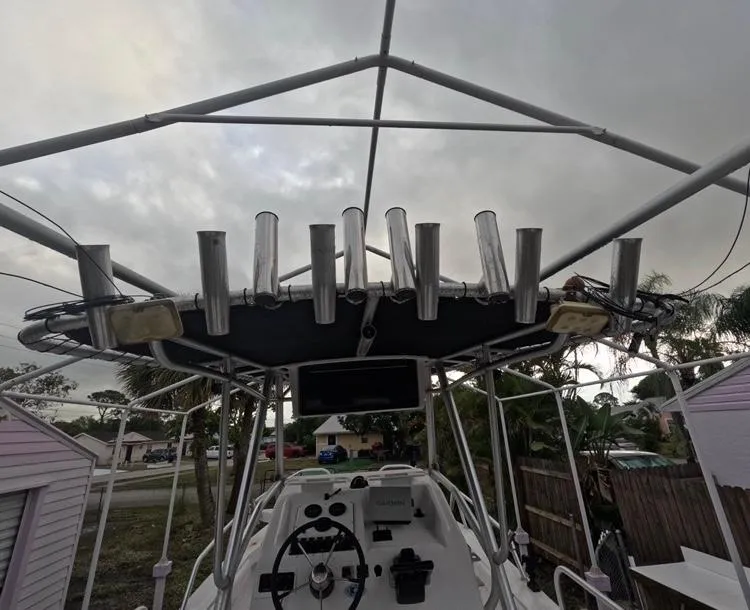 Slide: The Image of 2004 Twin Vee 26 Center Console boat with rod holders and canopy frame, parked outdoors. - 15