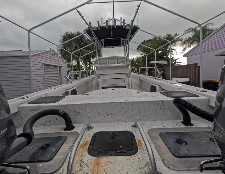 Slide: The Image of 2004 Twin Vee 26 Center Console boat, docked, with overcast sky and surrounding palm trees. - 11