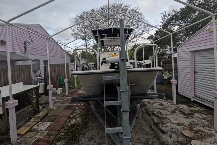 Slide: The Image of 2004 Twin Vee 26 Center Console boat stored in a backyard under a canopy. - 10