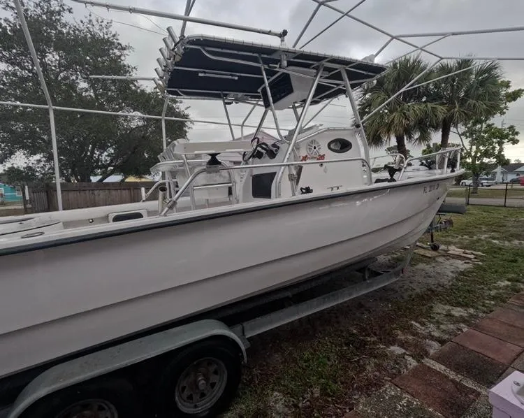 Slide: The Image of 2004 Twin Vee 26 Center Console boat on trailer, under canopy, with trees in background. - 7