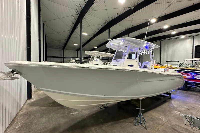 The Image of 2024 Cobia 301 Center Console boat displayed in a spacious indoor showroom. - 0