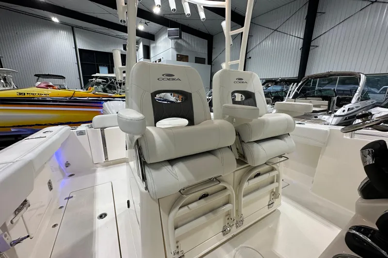 Slide: The Image of 2024 Cobia 301 Center Console boat interior with plush seating in a showroom. - 12