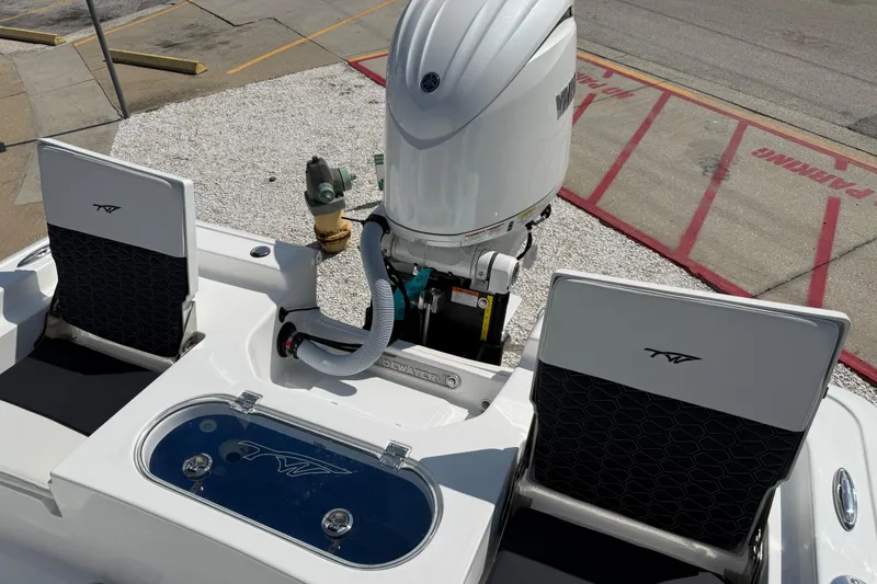 Slide: The Image of 2027 Tidewater 2110 Bay Max boat with outboard motor and seating, parked on gravel. - 8