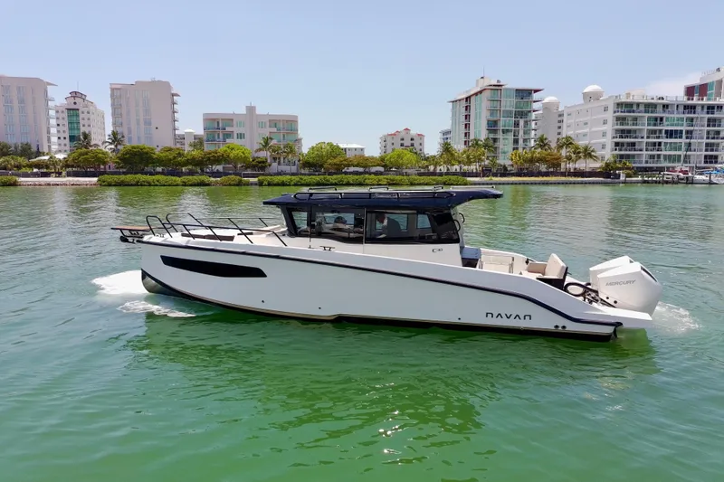 Slide: The Image of Navan C30 2026 boat cruising on a calm waterway with modern buildings in the background. - 2