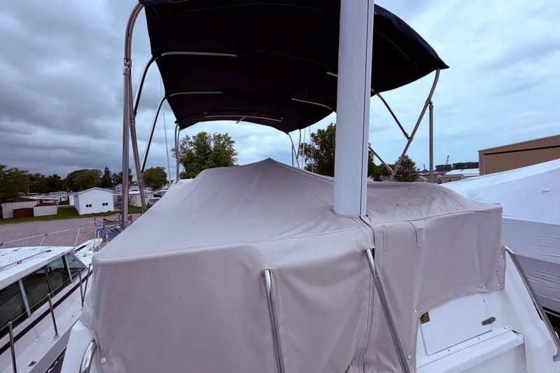 Slide: The Image of 1998 Sabreline 36 Fast Trawler with covered deck and canopy, docked under cloudy skies. - 12