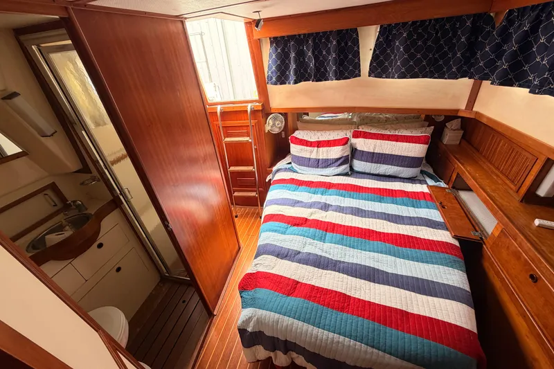 Slide: The Image of Cozy cabin interior of 1998 Sabreline 36 Fast Trawler with striped bedding and wooden accents. - 30