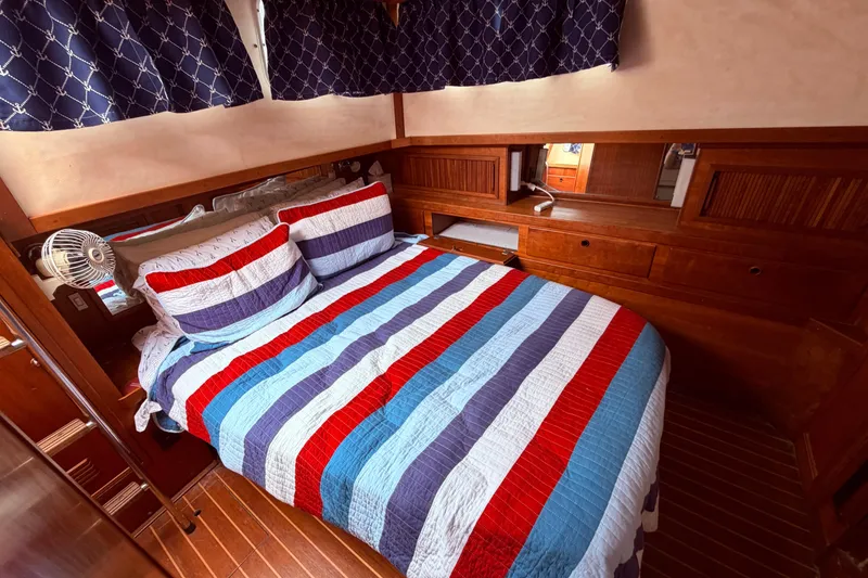 Slide: The Image of Cozy cabin bedroom in 1998 Sabreline 36 Fast Trawler with striped bedding and wooden accents. - 28