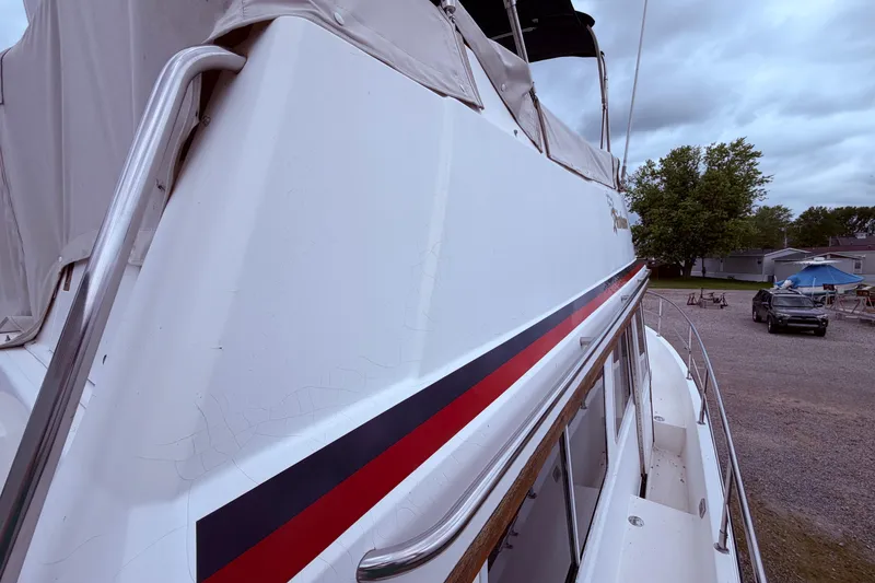 Slide: The Image of 1998 Sabreline 36 Fast Trawler with red and black stripe, docked under cloudy skies. - 13