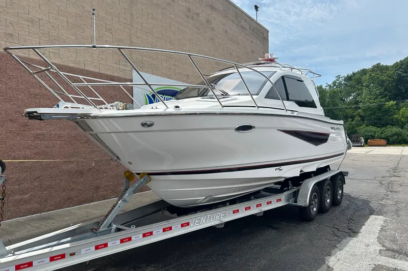 The Image of 2027 Solara S-250 Coupe boat on trailer, parked outdoors near a brick wall. - 0