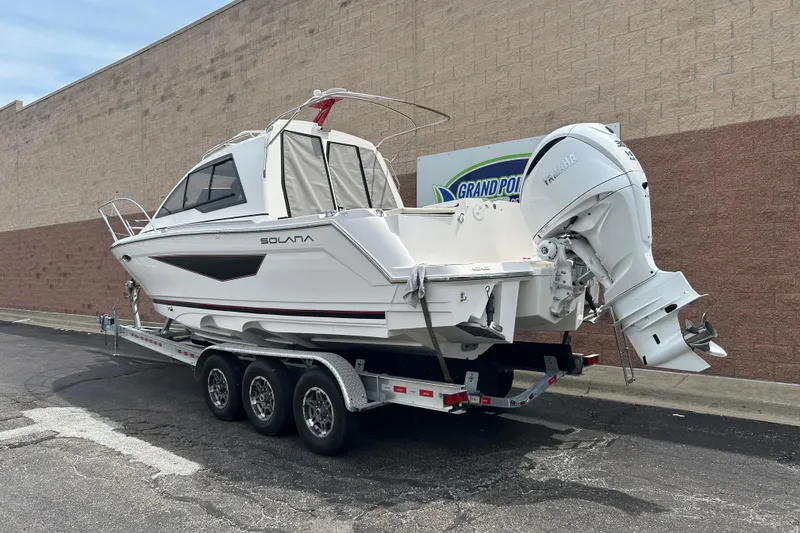 Slide: The Image of 2027 Solara S-250 Coupe boat on trailer, parked near a brick wall. - 2