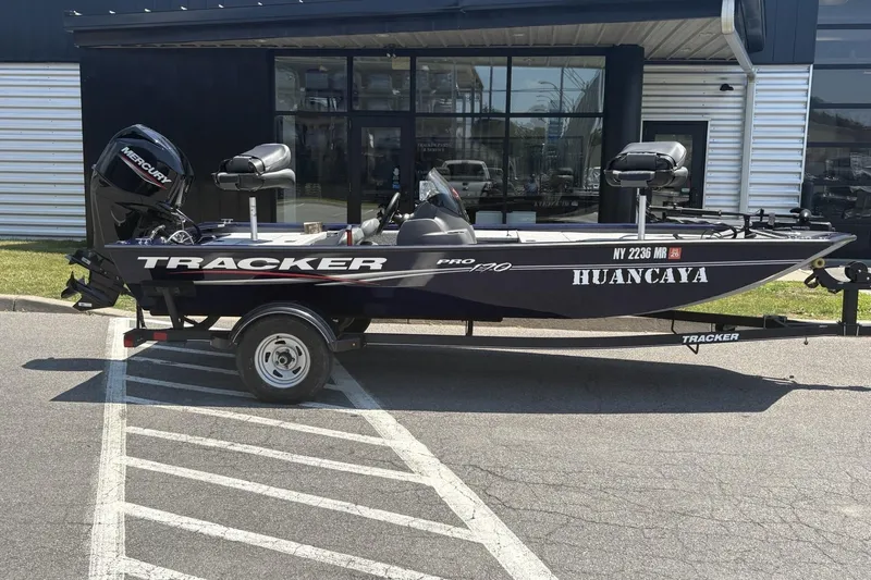 Slide: The Image of 2020 Tracker Pro 170 boat with Mercury engine parked outside a building. - 2