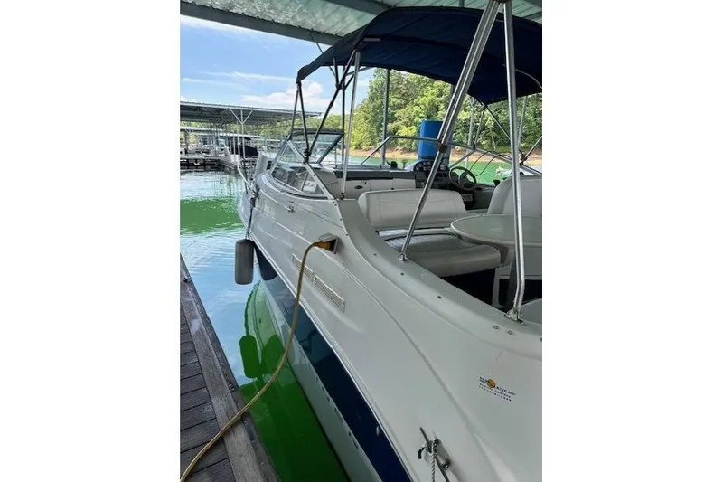 Slide: The Image of 2003 Bayliner 2655 Ciera docked under a canopy, with visible seating and steering wheel. - 3