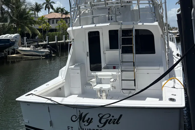 Slide: The Image of 2005 Hatteras 50 Convertible yacht docked, featuring a spacious deck and ladder. - 4