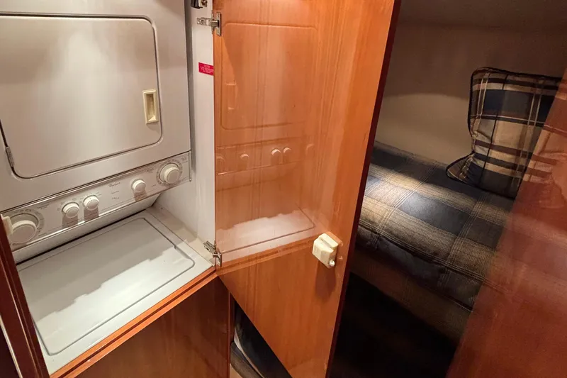 Slide: The Image of 2005 Hatteras 50 Convertible interior with washer-dryer and cozy plaid bedding. - 26