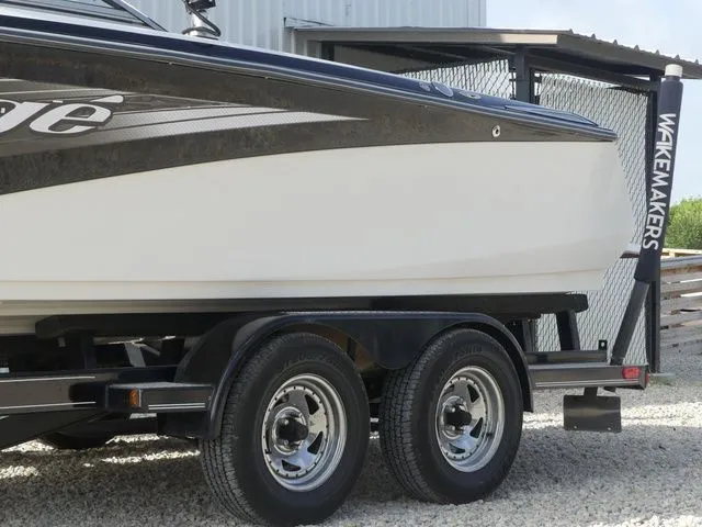 Slide: The Image of Side view of a 2008 Tigé Z1 boat on a trailer, featuring a black and white hull. - 9